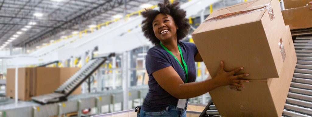 African American Woman moving a box down a sloped roller conveyor